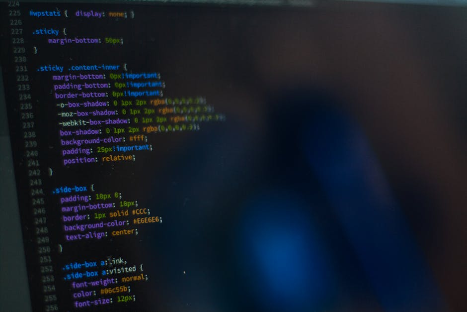 The image displays a close-up view of a computer screen showing lines of code with syntax highlighting in various colors such as yellow, blue, purple, and green. The code appears to be CSS styling det